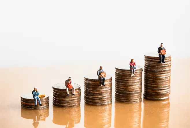 Miniature figurines of people sitting on piles of coins.