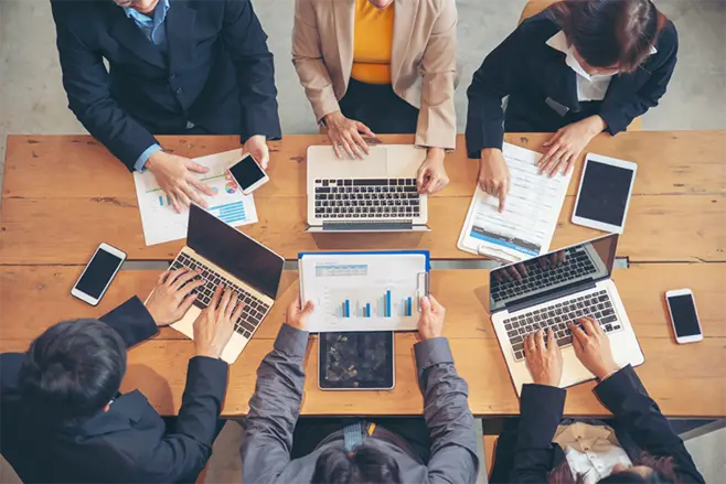 A group of people working at a table on computers.